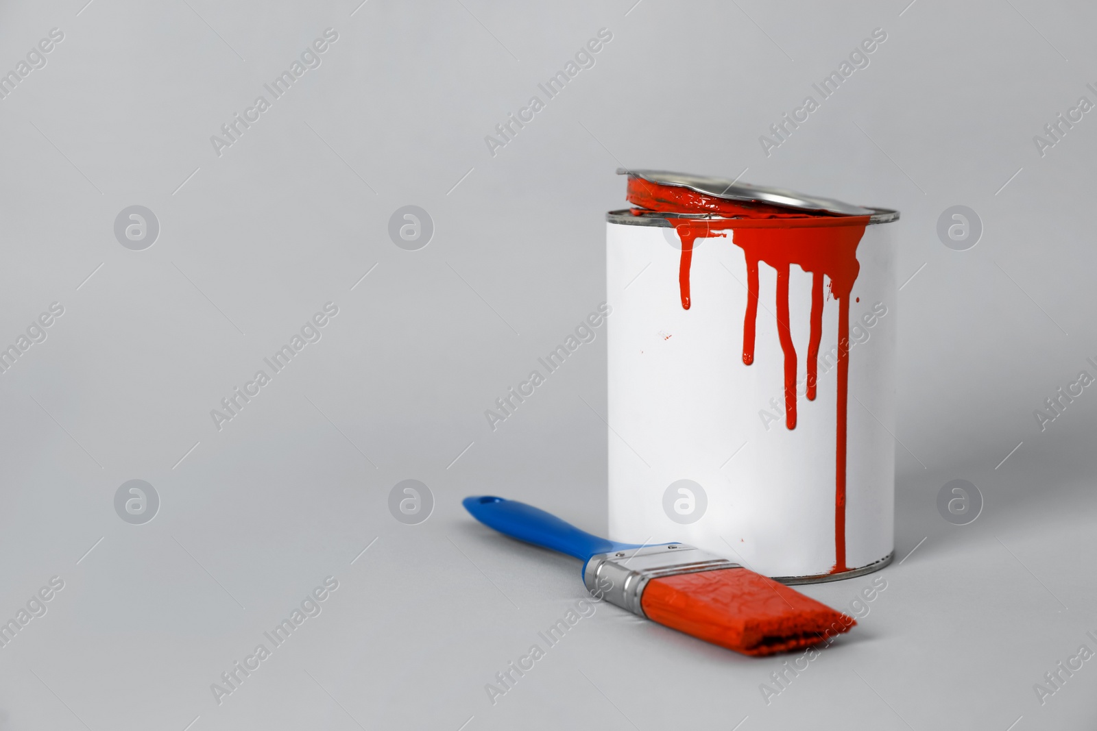 Photo of Can of orange paint and brush on grey background. Space for text