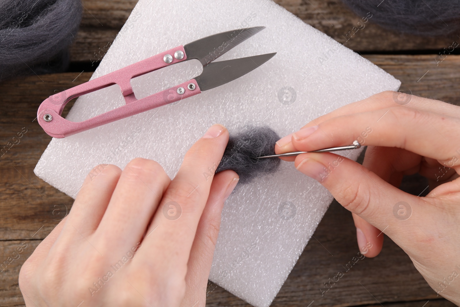 Photo of Woman felting from wool at wooden table, top view