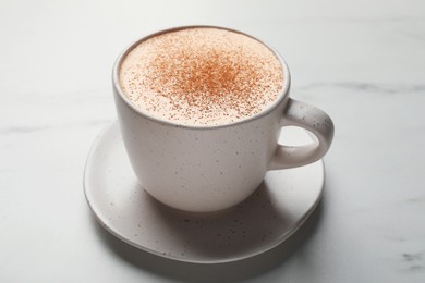 Delicious eggnog with cinnamon on white marble table, closeup