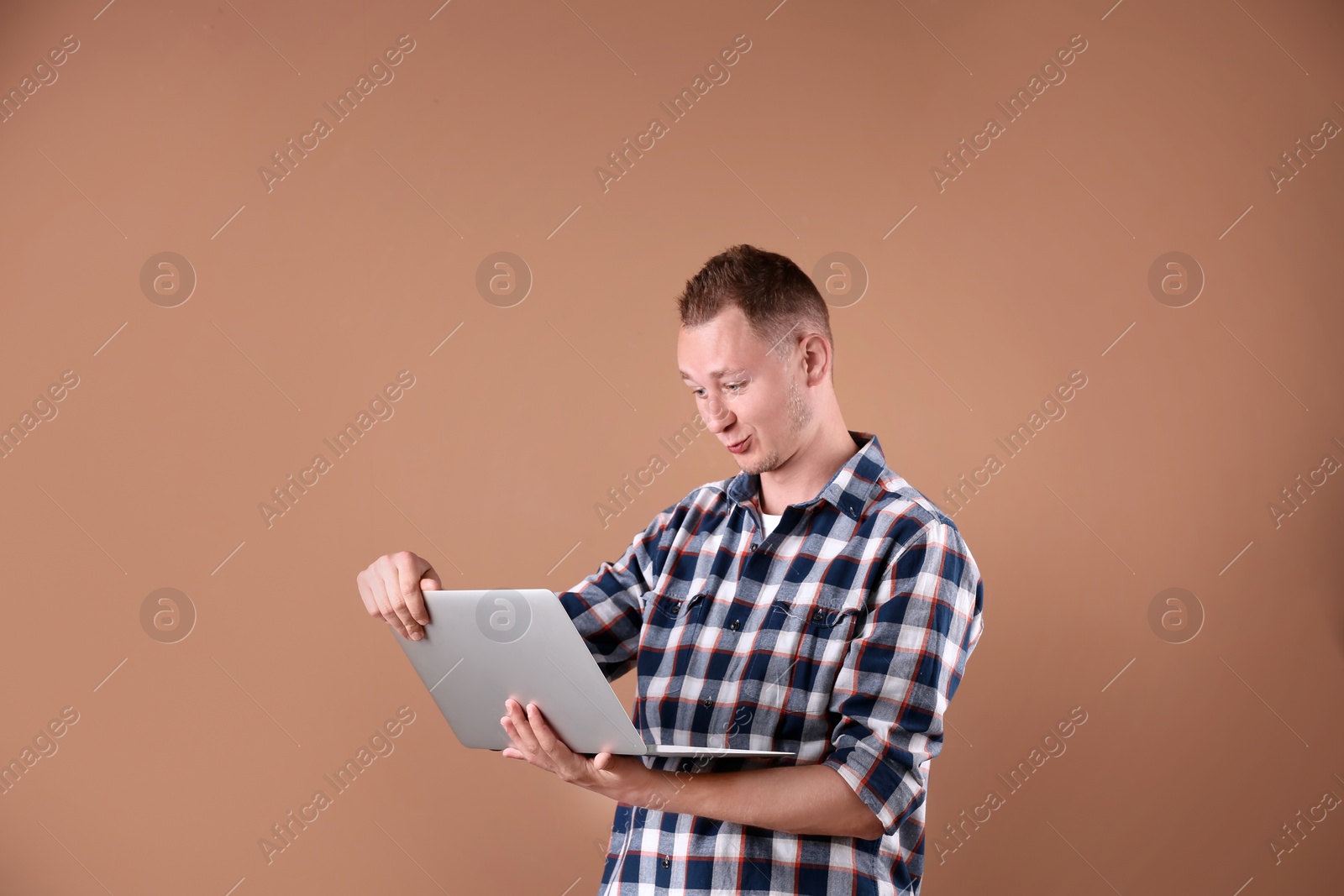 Photo of Portrait of handsome man with laptop on color background