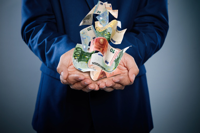 Image of Businessman with money on dark background, closeup. Currency exchange