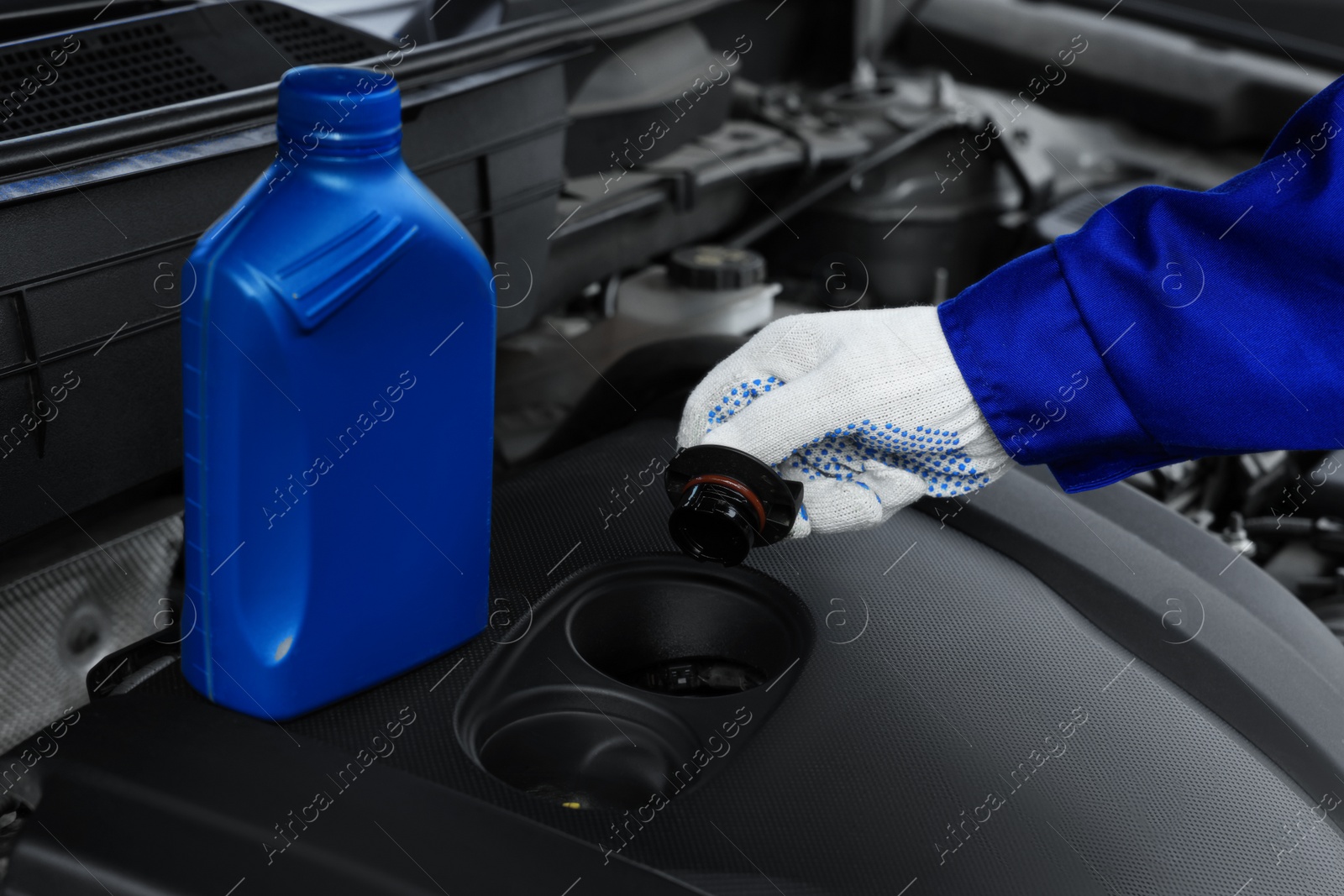 Photo of Worker checking motor oil level in car, closeup