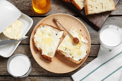Photo of Slices of bread with butter, honey and milk on wooden table, flat lay