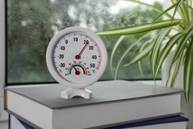 Photo of Round mechanical hygrometer on book near window