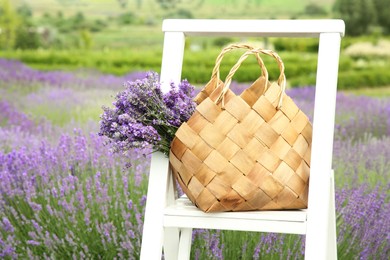 Photo of Wicker bag with beautiful lavender flowers on ladder in field