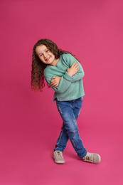 Full length portrait of cute little girl on pink background