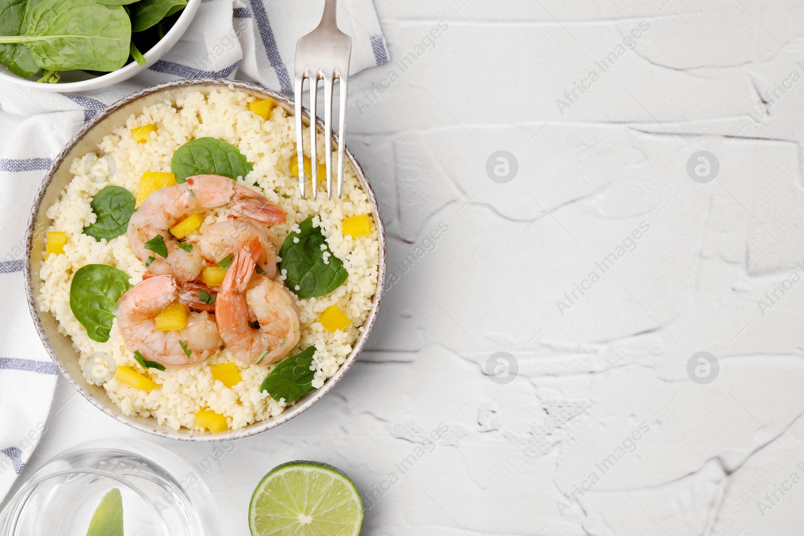 Photo of Tasty couscous with shrimps, bell pepper and basil served on white textured table, flat lay. Space for text
