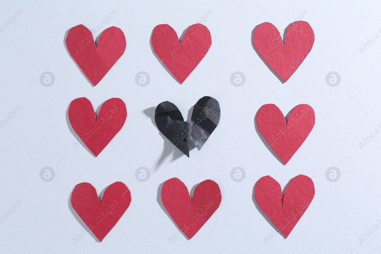 Photo of Halves of torn paper heart and red decorative hearts on gray background, flat lay. Breakup concept
