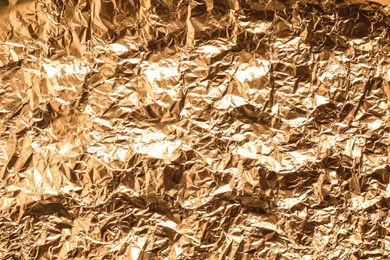 Photo of Crumpled gold foil as background, top view