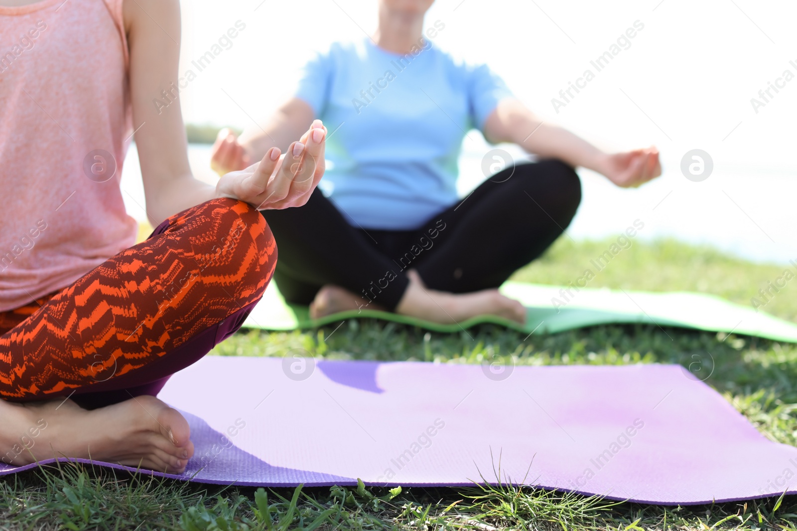 Photo of Group of women practicing yoga outdoors on sunny day