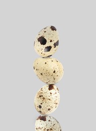 Image of Stacked speckled quail eggs on light grey background