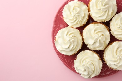 Photo of Tasty vanilla cupcakes with cream on pink background, top view. Space for text