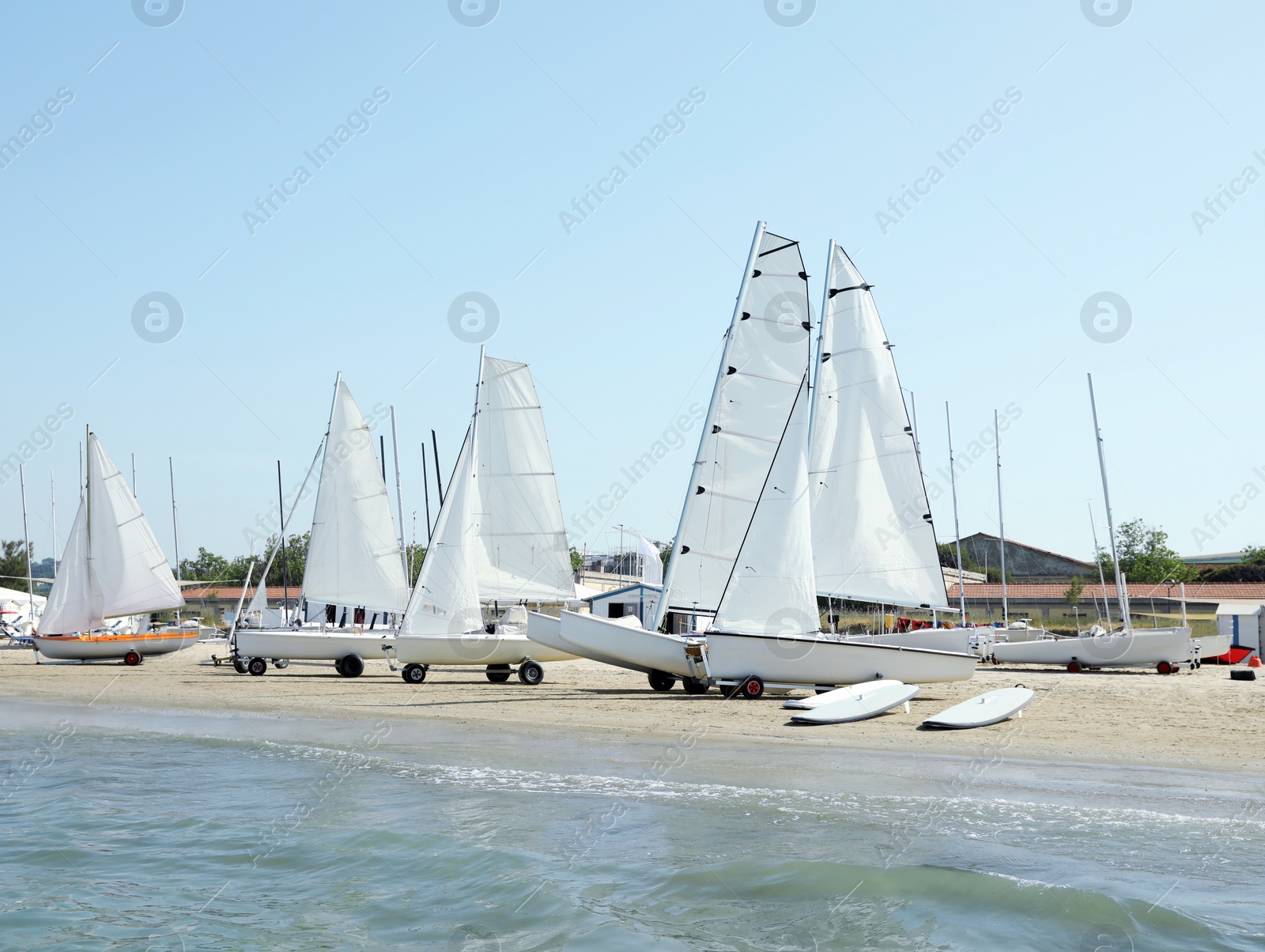 Photo of Seacoast with surf boards and modern yachts on sunny day