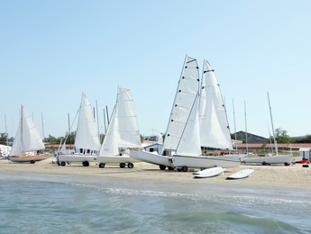 Photo of Seacoast with surf boards and modern yachts on sunny day