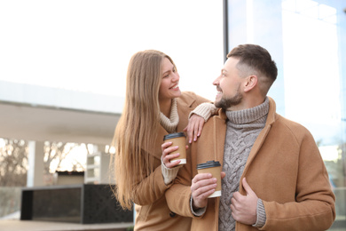 Photo of Lovely couple with cups of coffee on city street in morning