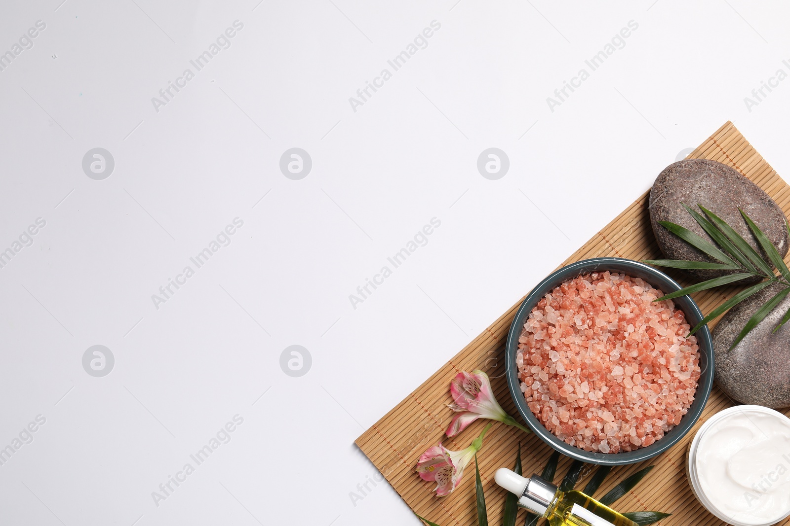 Photo of Natural sea salt in bowl and other spa products on white background, flat lay. Space for text
