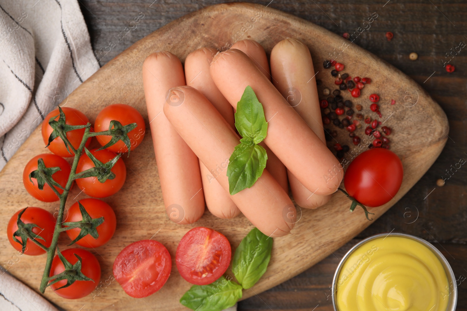 Photo of Delicious boiled sausages, sauce, tomatoes and spices on wooden table, flat lay