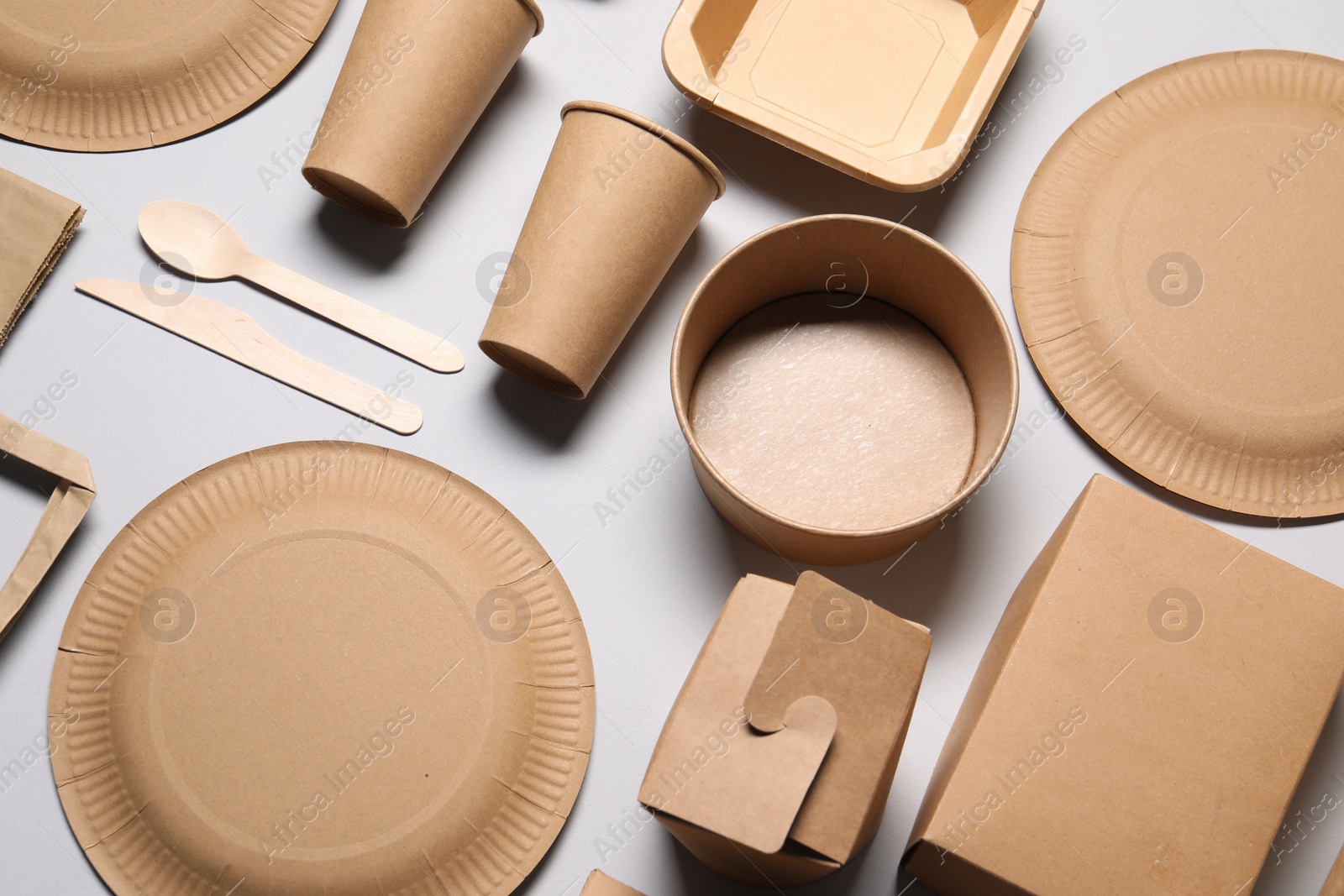 Photo of Eco friendly food packaging. Paper containers and tableware on light grey background, above view