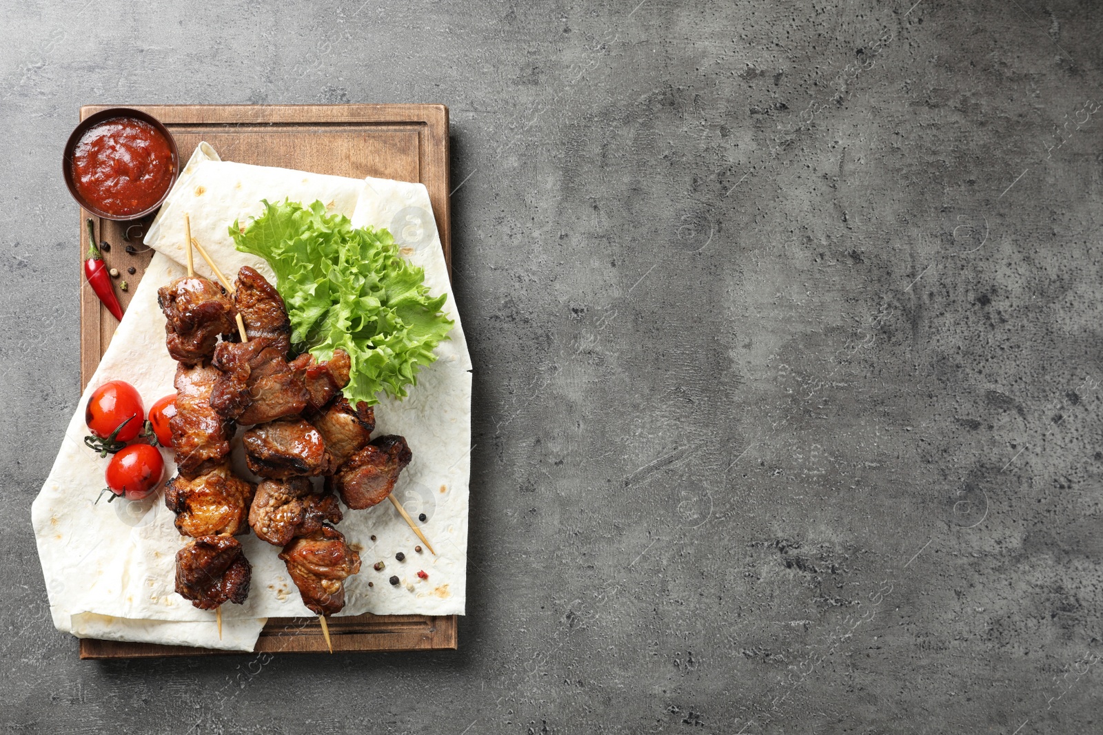 Photo of Delicious barbecued meat served on gray table. Space for text