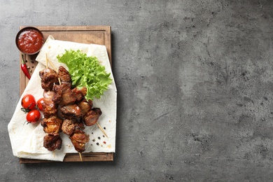 Photo of Delicious barbecued meat served on gray table. Space for text