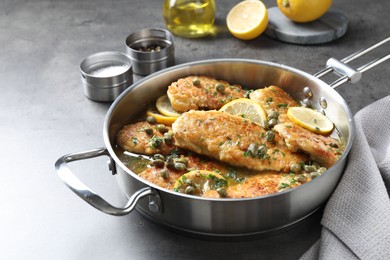 Delicious chicken piccata in pot on grey table