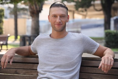 Photo of Handsome young man sitting on bench in park