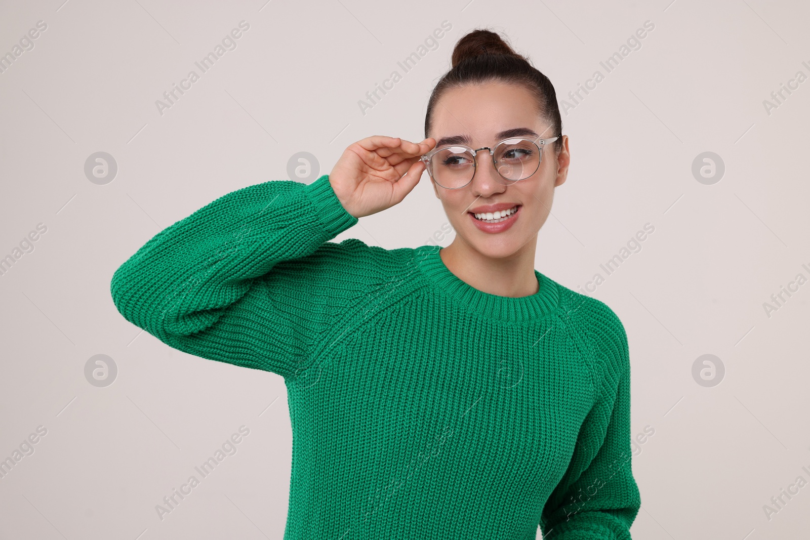 Photo of Beautiful young woman in stylish warm sweater on light grey background