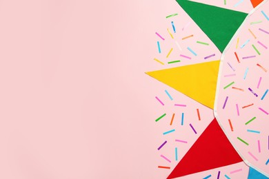 Bunting with colorful triangular flags and confetti on pink background, flat lay. Space for text