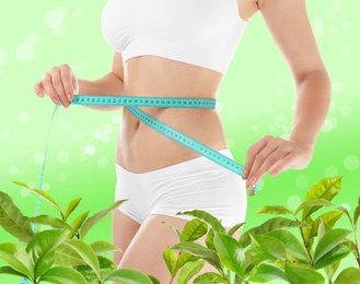 Image of Young woman measuring her waist on green background, closeup. Tea leaves for slimming drink