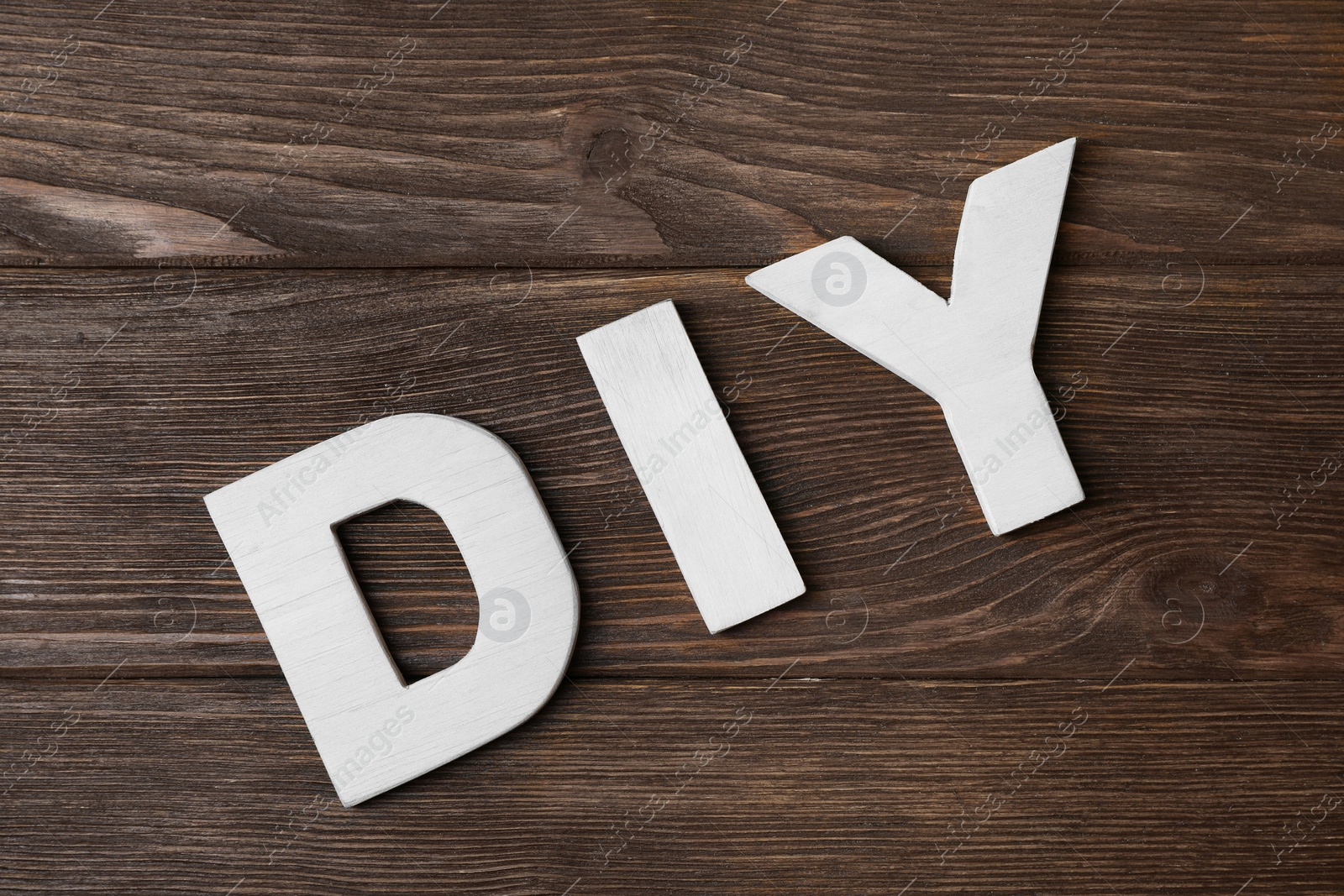 Photo of Abbreviation DIY made of letters on wooden table, flat lay