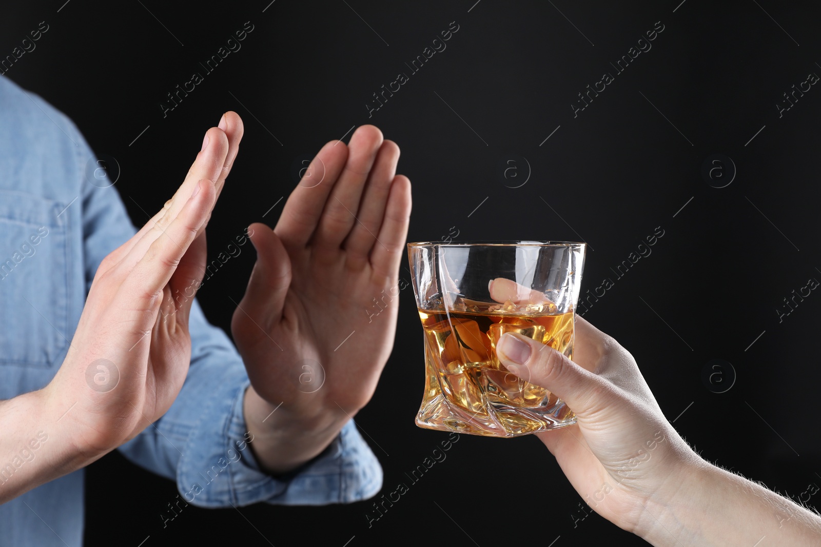 Photo of Alcohol addiction. Man refusing glass of whiskey on dark background, closeup