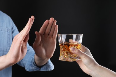 Photo of Alcohol addiction. Man refusing glass of whiskey on dark background, closeup