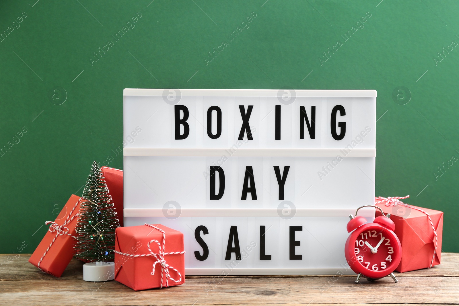 Photo of Composition with Boxing Day Sale sign and Christmas gifts on wooden table against green background