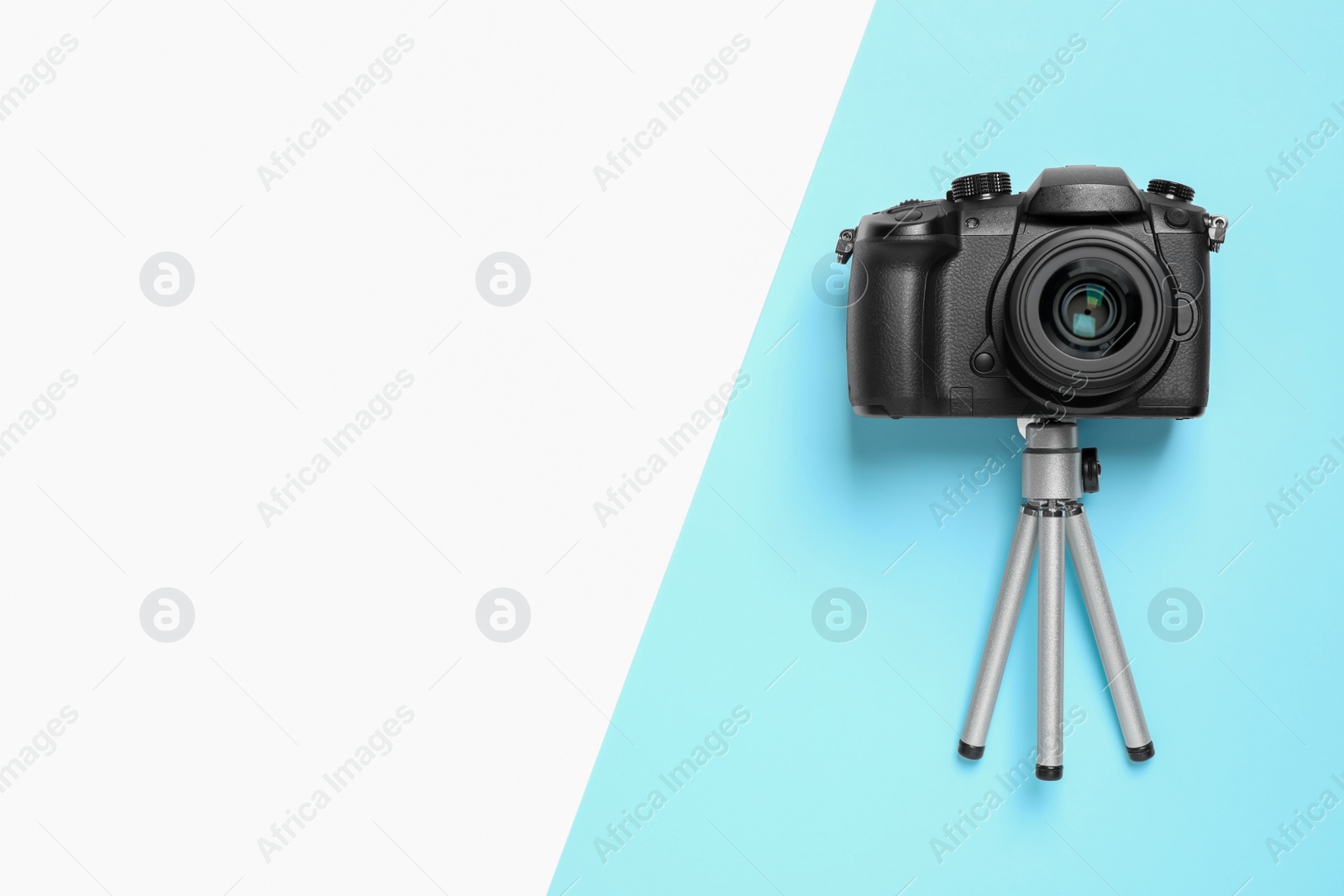 Photo of Modern camera and mini tripod on color background, flat lay with space for text. Video production equipment