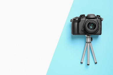 Modern camera and mini tripod on color background, flat lay with space for text. Video production equipment