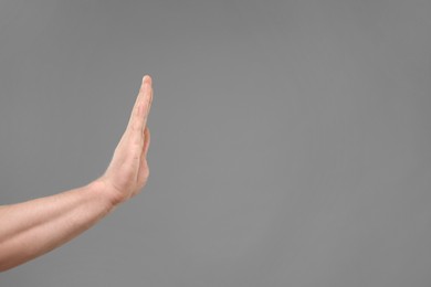 Photo of Man showing stop gesture on grey background, closeup. Space for text