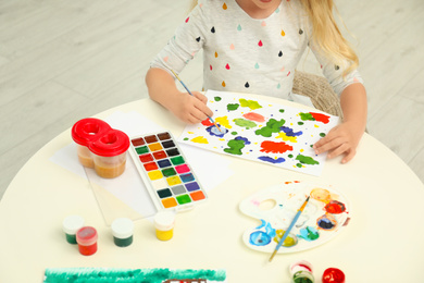 Cute little child painting at table in room