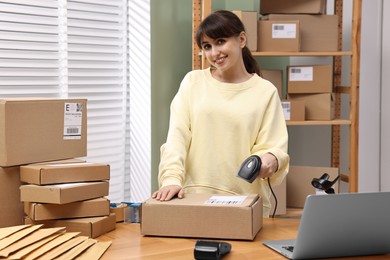 Photo of Parcel packing. Post office worker with scanner reading barcode indoors