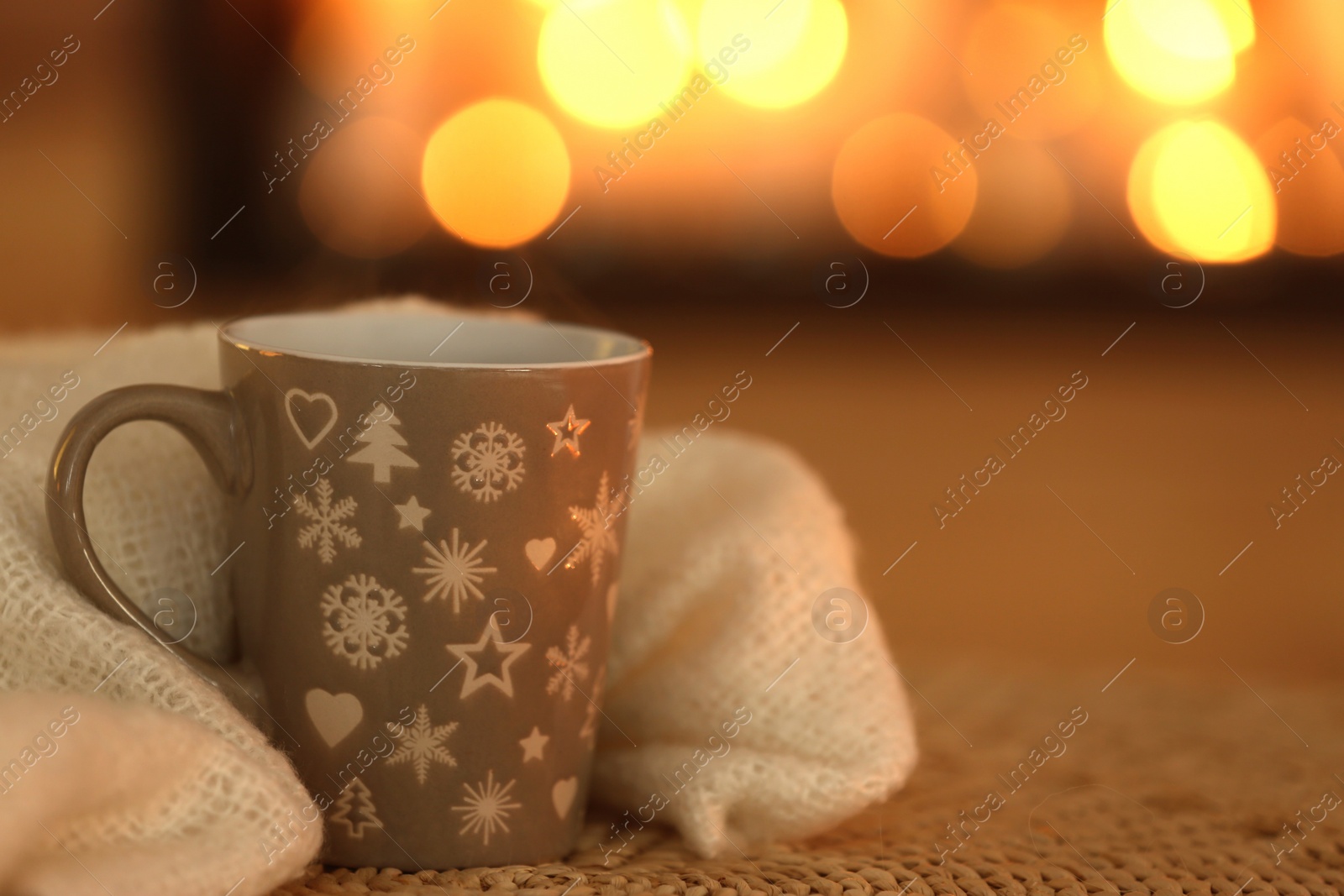 Photo of Cup of hot drink on wicker mat against blurred background. Winter atmosphere