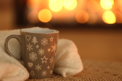 Photo of Cup of hot drink on wicker mat against blurred background. Winter atmosphere