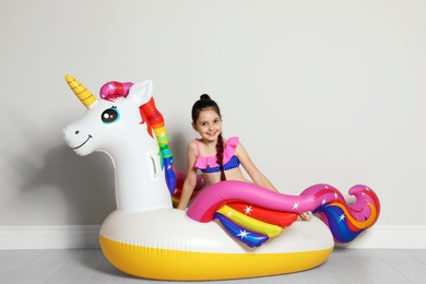 Cute little girl on bright inflatable ring near light wall
