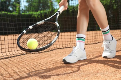 Woman with tennis racket and ball on court, closeup