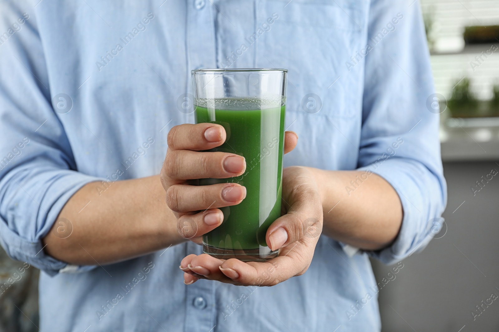 Woman holding glass of wheat grass juice, closeup Photo of Woman holding glass of wheat grass juice, closeup