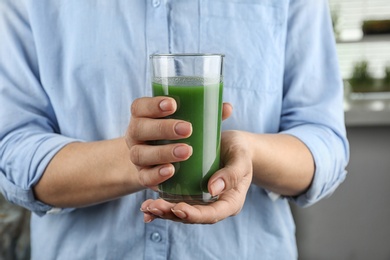 Photo of Woman holding glass of wheat grass juice, closeup