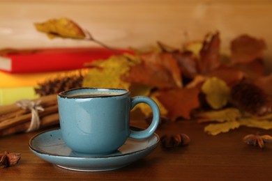 Photo of Composition with cup of hot coffee and autumn leaves on wooden table, space for text