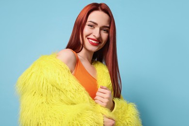 Happy woman with red dyed hair on light blue background