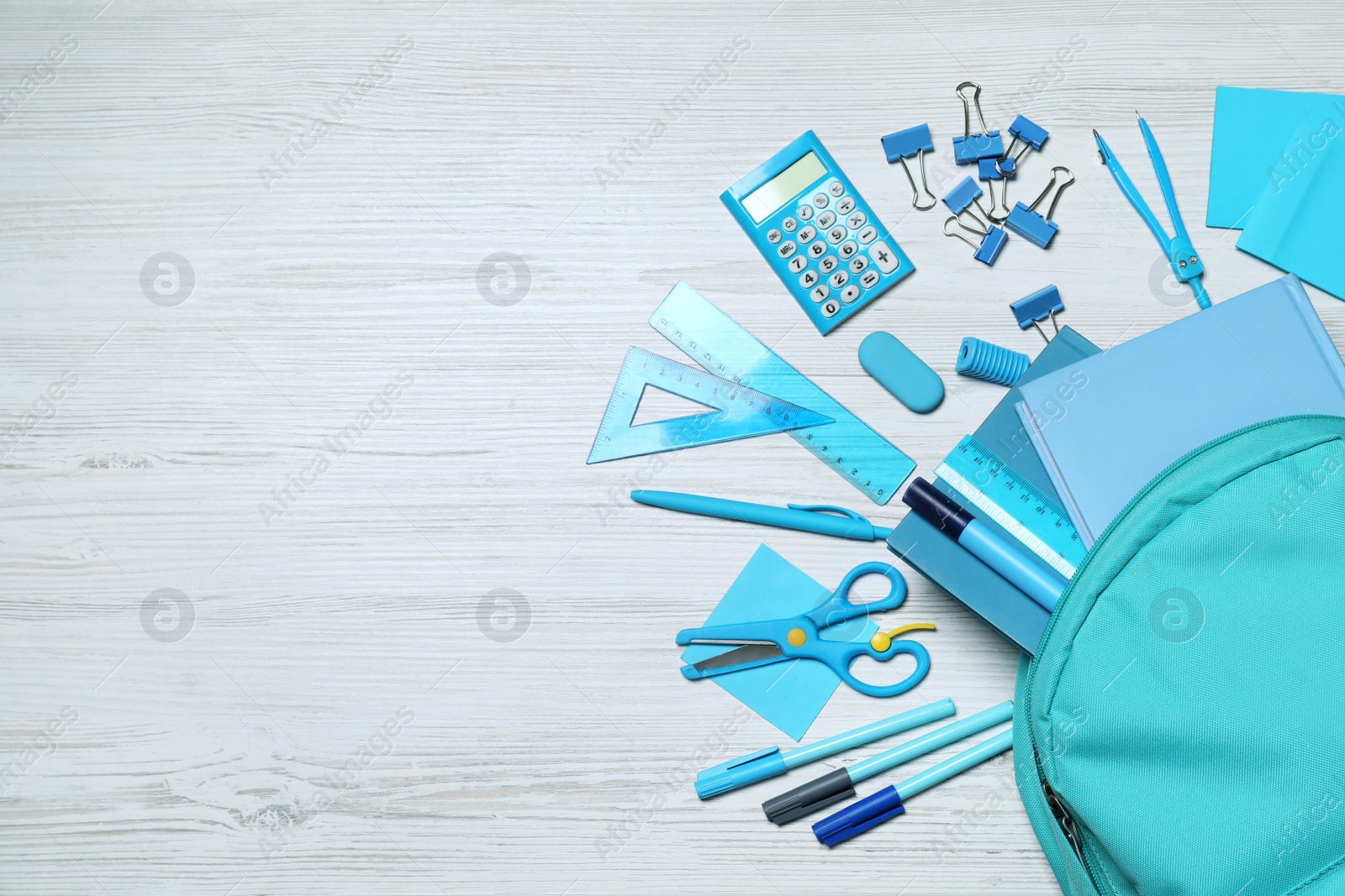 Photo of Flat lay composition with backpack and school stationery on white wooden background, space for text