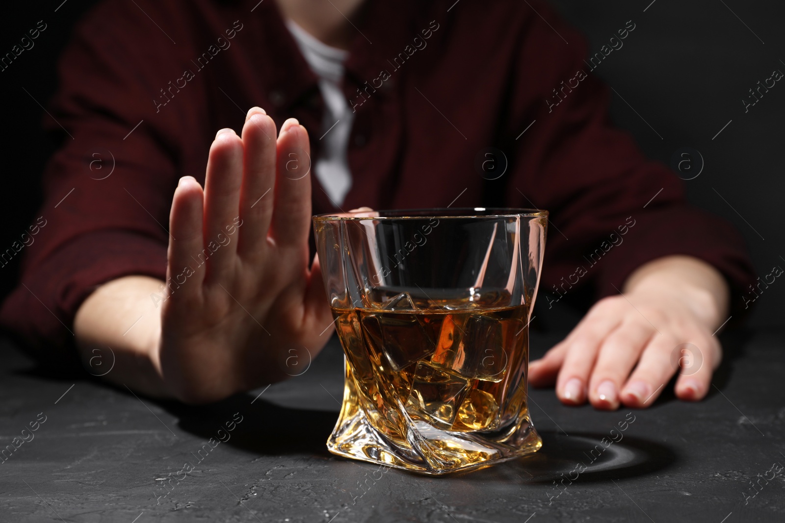 Photo of Alcohol addiction. Woman refusing glass of whiskey at dark textured table, closeup