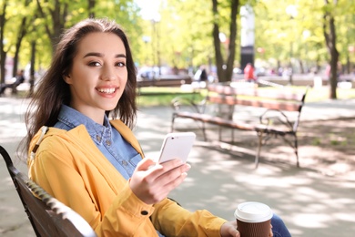 Photo of Young woman using phone outdoors on sunny day