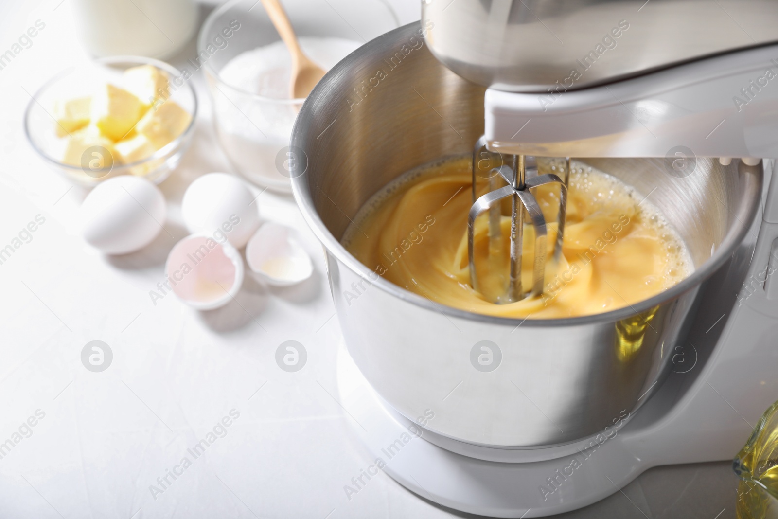 Photo of Making dough in bowl of stand mixer on white table, closeup. Space for text